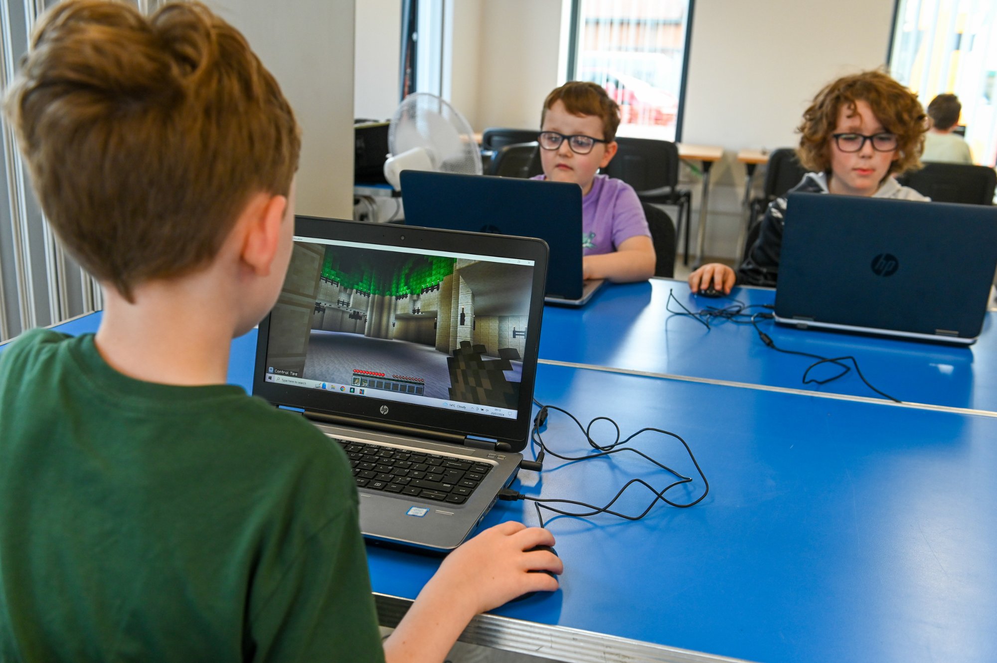 3 students sat at laptops during minecraft class